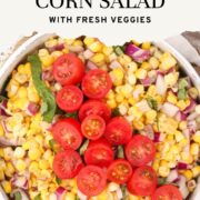 Easy Corn Salad in a white bowl and garnished with basil and cherry tomatoes.