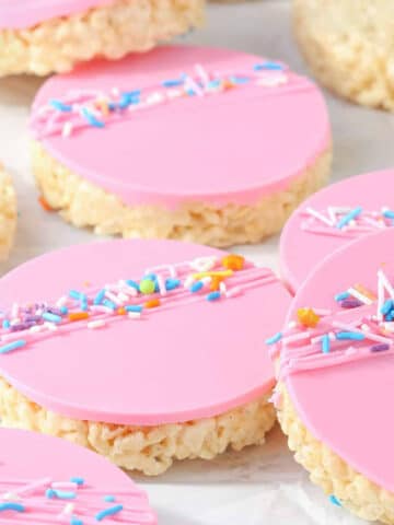 Rice Krispie Treats with pink melted chocolate layer topped with sprinkles.