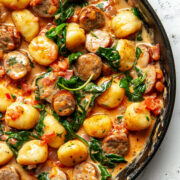 Crispy air fryer gnocchi skillet with golden brown gnocchi, Italian chicken sausage, fresh spinach, and creamy tomato sauce served in a cast iron pan