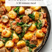 Crispy air fryer gnocchi skillet with golden brown gnocchi, Italian chicken sausage, fresh spinach, and creamy tomato sauce served in a cast iron pan