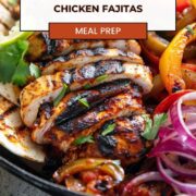 Sliced grilled chicken breast with char marks, sautéed bell peppers and red onions, served in a cast iron skillet with warm tortillas, lime wedge, and fresh cilantro.