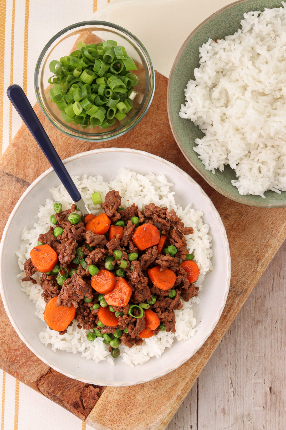 Quick Korean beef bowl with ground beef, carrots, peas, and green onions served over white rice.