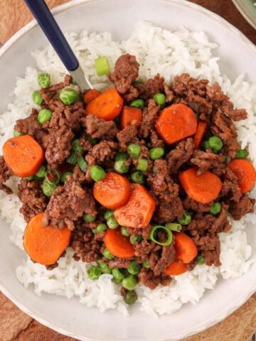 Quick Korean beef bowl with ground beef, carrots, peas, and green onions served over white rice.