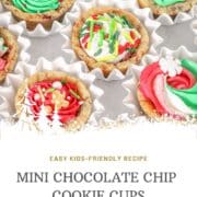 Overhead view of mini chocolate chip cookie cups baked in a mini muffin pan and filled with colorful buttercream frosting and Christmas sprinkles, arranged in white paper cups.