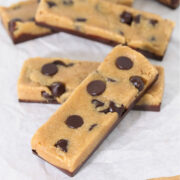 Peanut butter chocolate protein bars with chocolate chips and a chocolate base, arranged on parchment paper to show their soft, doughy texture and Perfect Bar–style shape.