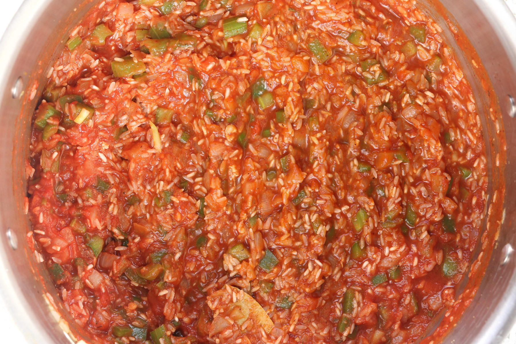 Raw rice stirred into the tomato and broth mixture before simmering jambalaya.