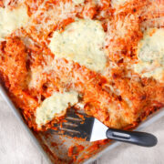 Weeknight sheet pan lasagna baked in a rimmed pan with crispy edges, melted mozzarella cheese, dollops of creamy ricotta, and rich marinara sauce, showing golden cheesy edges and crisp bites perfect for easy individual portions.