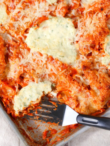 Weeknight sheet pan lasagna baked in a rimmed pan with crispy edges, melted mozzarella cheese, dollops of creamy ricotta, and rich marinara sauce, showing golden cheesy edges and crisp bites perfect for easy individual portions.