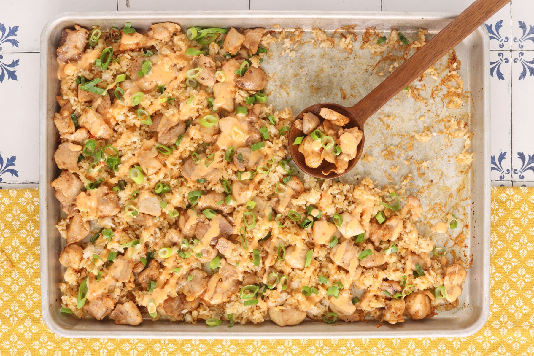 Sheet pan bang bang chicken with crispy rice, creamy bang bang sauce and sliced green onions, served straight from the pan.