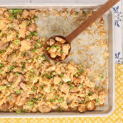 Sheet pan bang bang chicken with crispy rice, drizzled with creamy bang bang sauce and topped with sliced green onions.