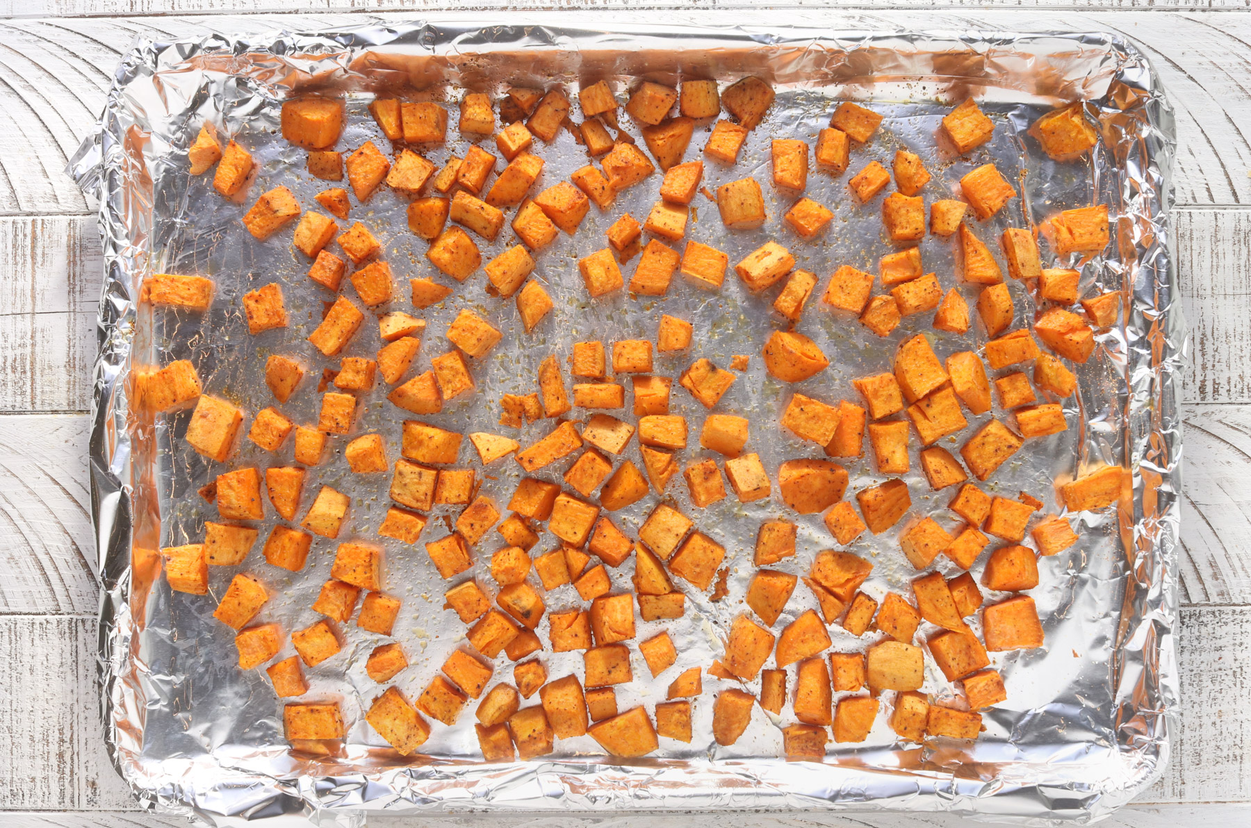 roasted sweet potatoes spread on a baking sheet for burger bowls
