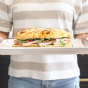 Turkey bacon pesto focaccia sandwich with provolone and arugula, held on a sheet pan.