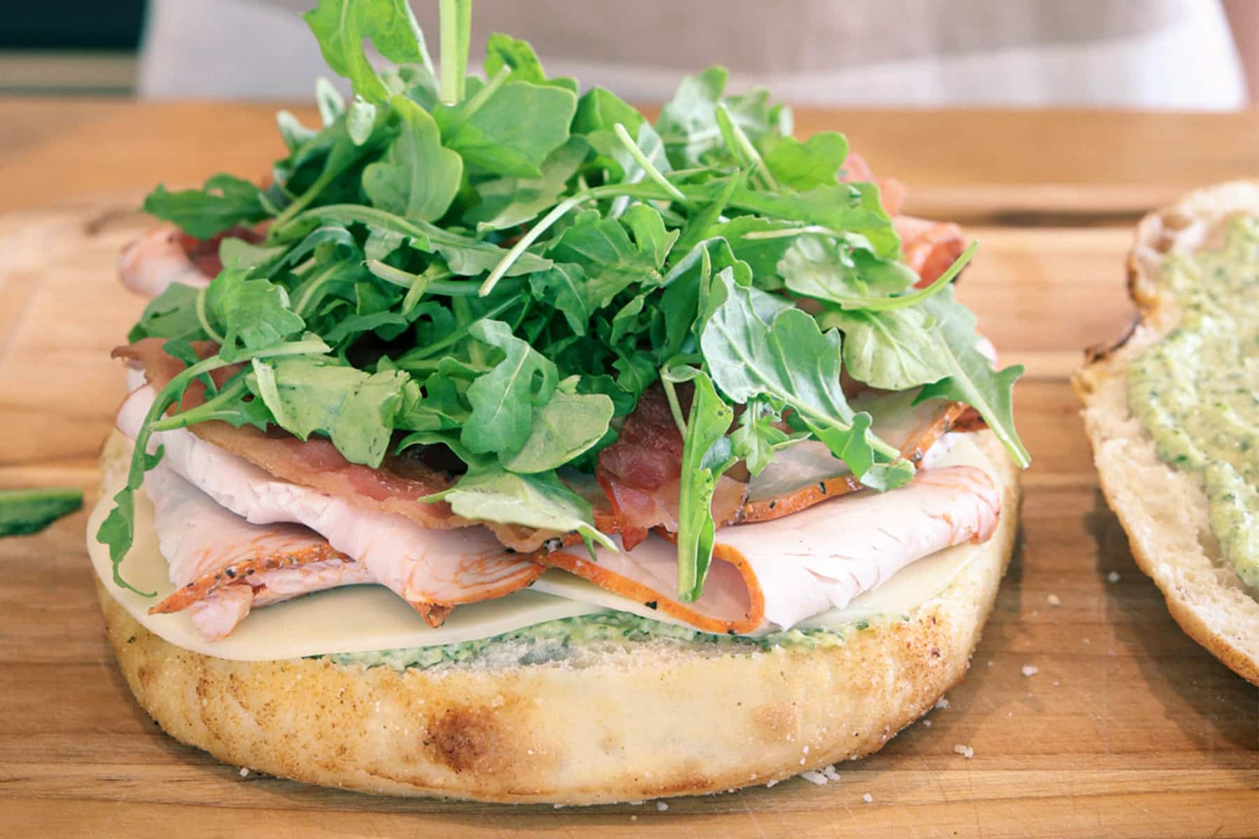 Open turkey bacon pesto focaccia sandwich layered with provolone, deli turkey, crisp bacon, arugula, and pesto mayo.