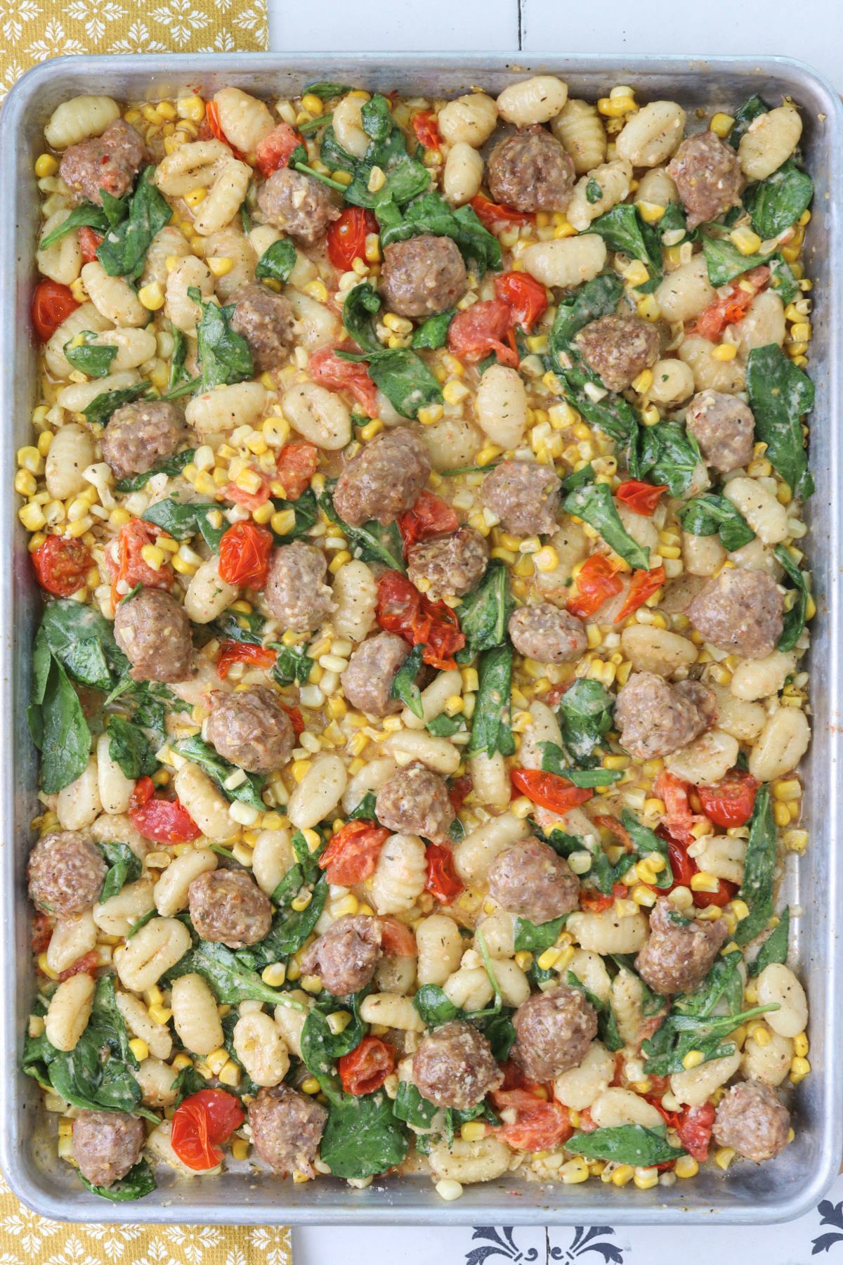 Sheet pan gnocchi with Italian sausage, cherry tomatoes, fresh corn, and wilted spinach.