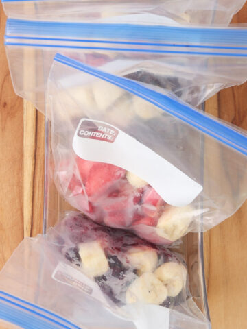 Make-ahead freezer smoothie packs with frozen strawberries, blueberries and banana portioned into zip-top bags.