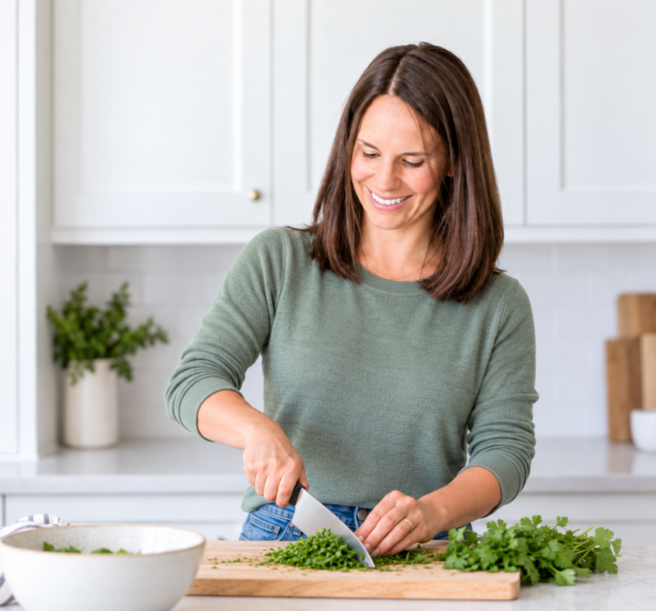 bailey chopping herbs in a green sweater.