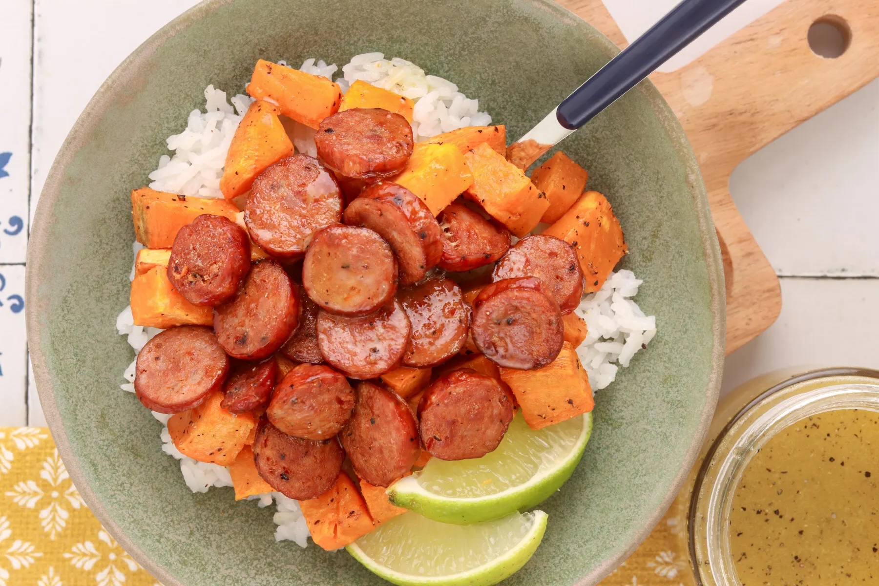 Honey-lime chicken sausage bowl with roasted sweet potatoes, white rice and lime wedges, served with honey-lime dressing.
