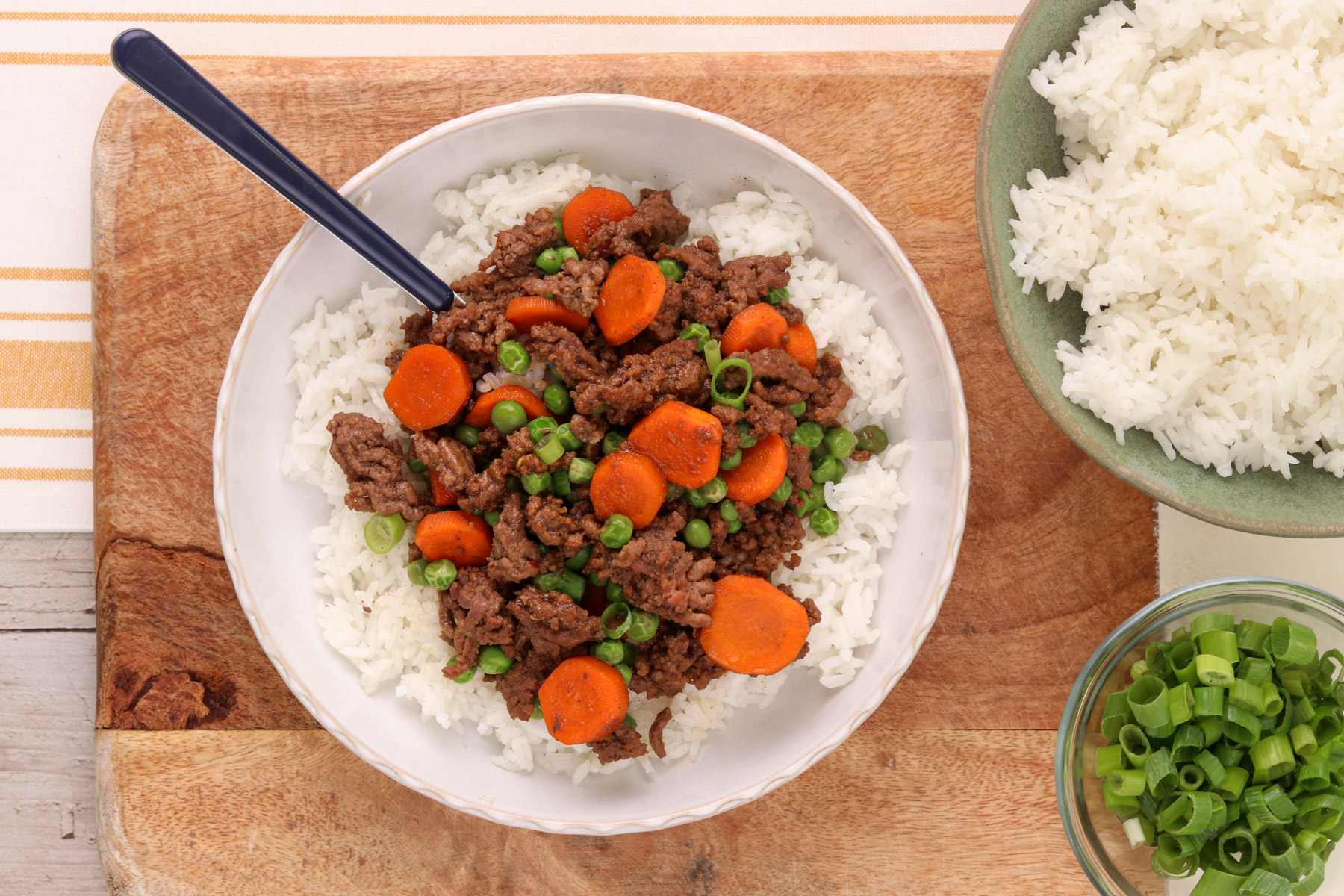 step 4 - Quick Korean beef bowl with ground beef, carrots, peas, and green onions served over white rice.