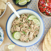 Slow cooker Mexican shredded chicken with lime and cilantro, served with tortillas, rice, tortilla chips, pico de gallo, and lime wedges.