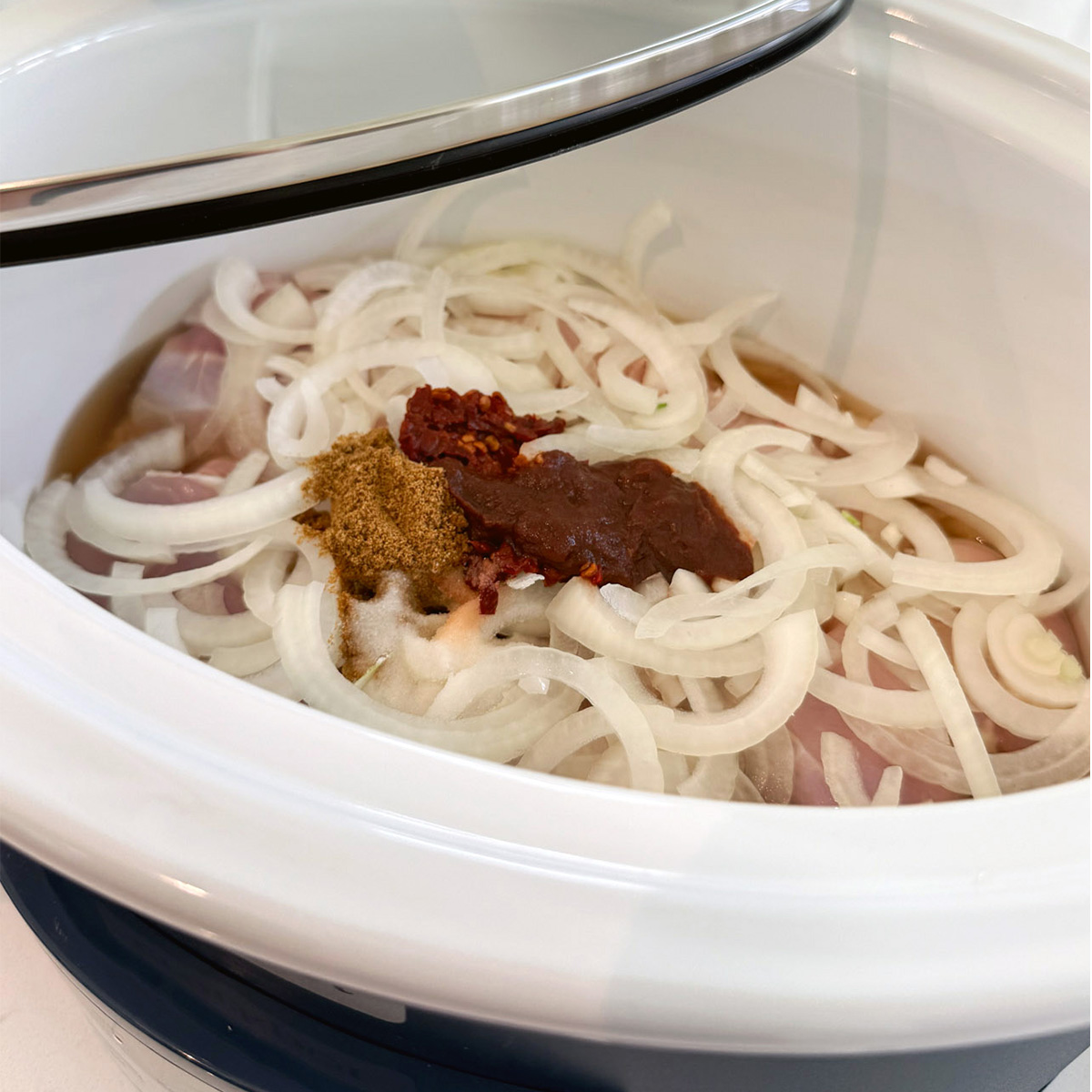 Chicken thighs, sliced onion, chipotle pepper, adobo sauce, cumin and broth added to a slow cooker.