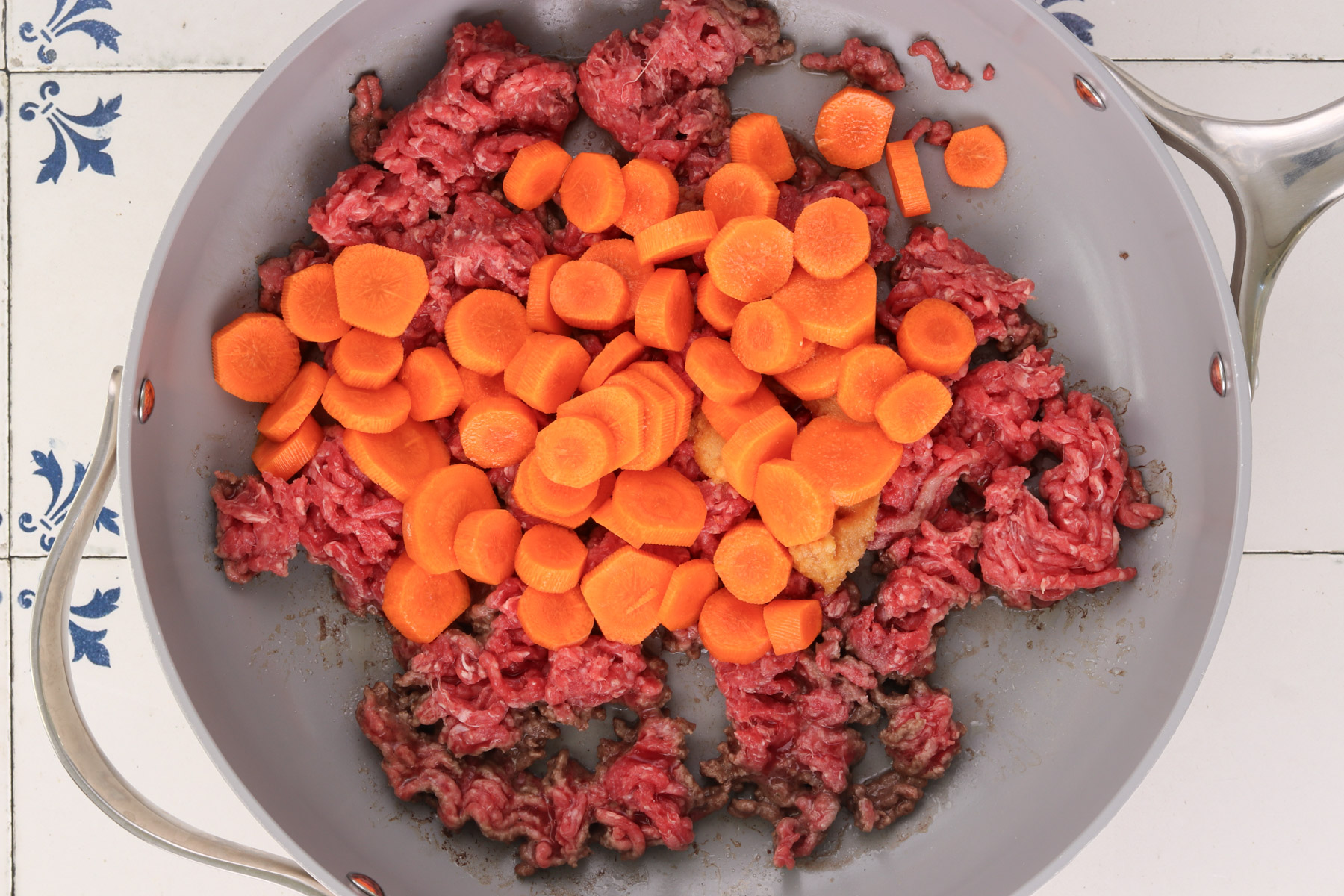 Ground beef and sliced carrots cooking together in a skillet for quick Korean beef bowls.