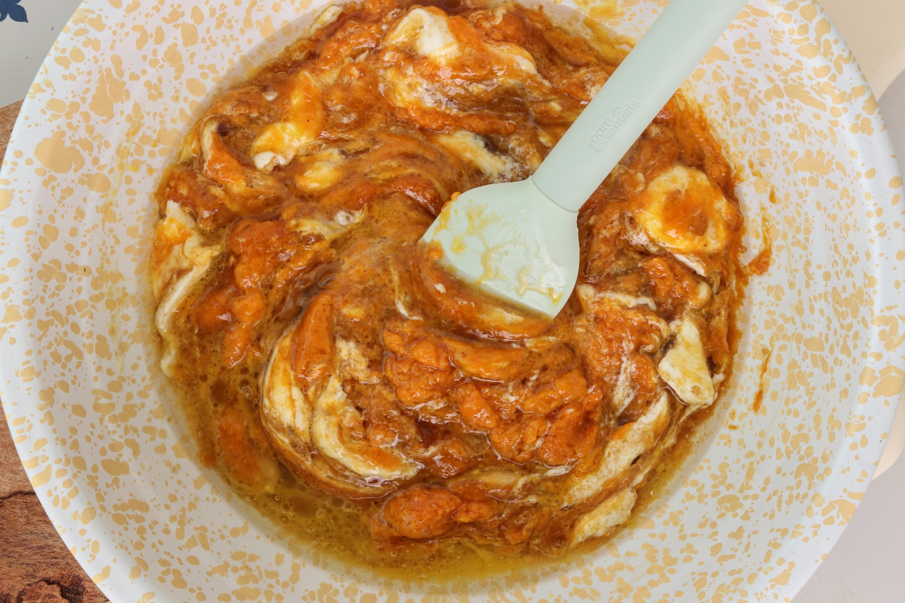 Wet ingredients for pumpkin protein muffins, including pumpkin puree, Greek yogurt, eggs, brown sugar, oil and vanilla, being stirred together in a mixing bowl.
